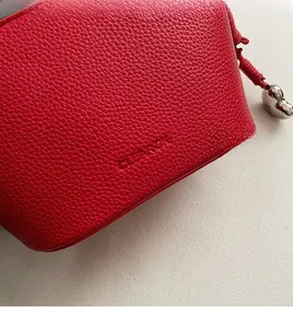 Detail of red lychee grain leather bag featuring CLEAROK logo and metal heart charm