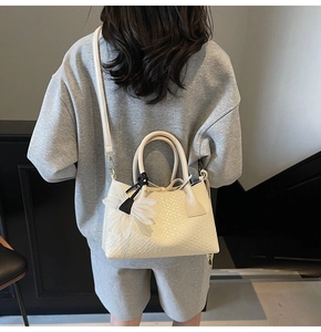 Off-white woven textured handbag with floral charm shown in a lifestyle model shot