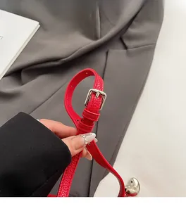 Detail of red litchi grain leather shoulder strap with adjustable silver metal buckle