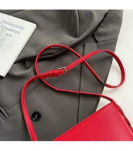 Detail of red lychee pattern leather bucket bag with silver buckle on a grey suit