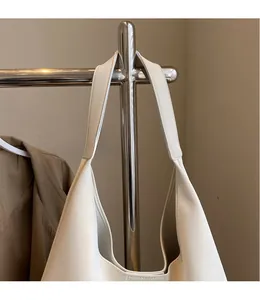 Detail of wide smooth leather shoulder strap on a white minimalist hobo tote bag