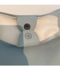 Macro shot of silver magnetic snap closure on a soft leather tote bag with precise stitching
