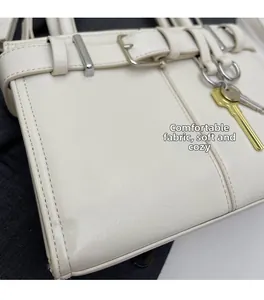 Détail du sac à bandoulière blanc cassé en similicuir avec boucle et breloque clé