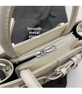 Détail de la fermeture éclair en métal argenté sur le sac à main en cuir PU beige crème