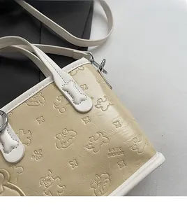 Détail du cabas en cuir crème avec embossage de chien cartoon et logo de marque