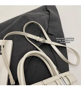 Détail d'un sac à main crème avec bandoulière réglable et boucle métallique argentée