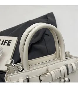 Détail d'un sac à main en cuir blanc crème avec fermeture éclair argentée et anses
