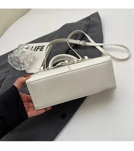 Détail d'un sac rectangulaire blanc en cuir avec poignée solide et bandoulière réglable