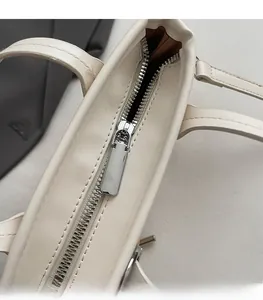 Détail de la fermeture éclair en métal argenté lisse du sac seau minimaliste blanc crème