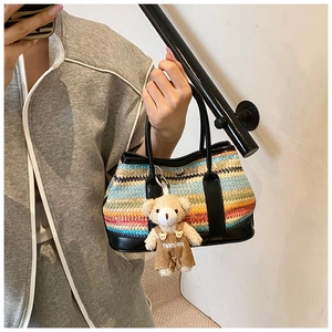Close-up of colorful striped knit shoulder bag featuring a cute teddy bear charm