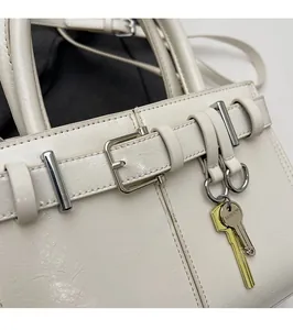 Détail du sac crème avec boucle de sangle en cuir et porte-clés métallique 'FASHION'