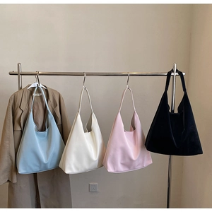 Minimalist large Hobo shoulder bags in blue, white, pink and black hanging on a metal rack