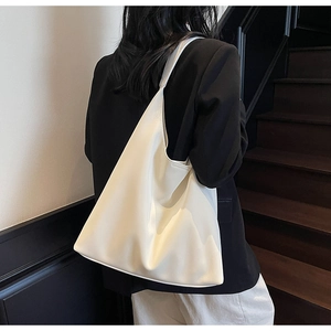 Minimalist cream white leather tote bag shown in a stylish shoulder carrying scene