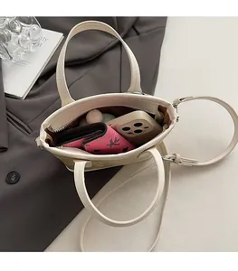 Gros plan sur l'intérieur spacieux et le motif gaufré du sac cabas de couleur crème