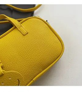 Detailed shot of yellow litchi grain leather bag with a cute smiley face charm