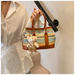 Détail du sac à main tissé à rayures bohèmes avec poignées en cuir et breloque ours