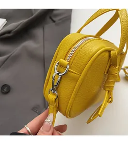 Detail of yellow lychee leather bag featuring silver hardware and durable carabiner clip