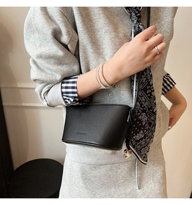 Detail of black lychee grain leather bucket bag with silk scarf and metal charm