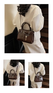 Détail de la texture cuir verni marron foncé et de la boucle argentée du sac à main