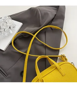 Detail of yellow lychee texture leather handbag with reinforced handle on a blazer