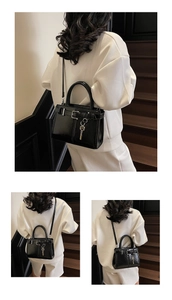 Détail du sac à bandoulière noir brillant avec porte-clés argenté et boucle