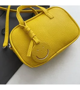 Close-up of yellow lychee grain leather handbag with smiley face pendant detail