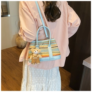 Detail of colorful woven straw bucket bag featuring a blue leather strap and cute bear charm