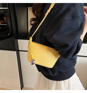 Detail of yellow litchi leather crossbody bag with silver heart charm and adjustable strap
