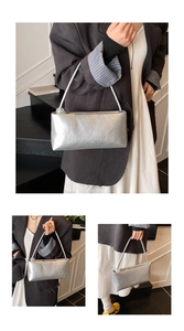 Detail of silver metallic baguette bag featuring unique pleated texture and brand logo