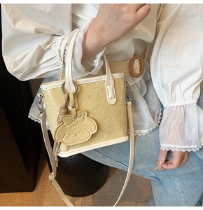 Détail de l'embossage mignon de chiot sur le sac cabas en similicuir de couleur crème