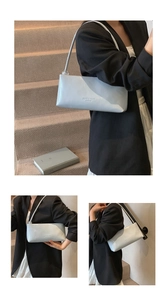 Detail of light blue baguette bag showing embossed logo and clear sphere strap accent