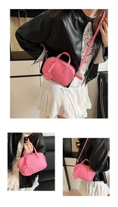 Detail of pink pebbled leather crossbody bag featuring a round smile charm pendant