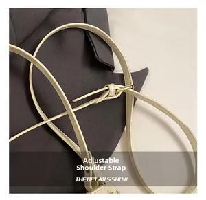 Détail de la bandoulière réglable en cuir crème avec boucle dorée et finitions de précision