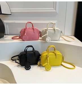 Close-up of four colored leather crossbody bags with smiley face charms in a studio set