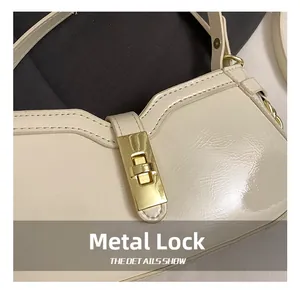 Détail du fermoir rotatif doré élégant sur un sac à bandoulière blanc crème chic