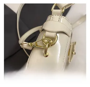 Détail du sac en cuir verni crème avec crochet en métal doré et attache de bandoulière