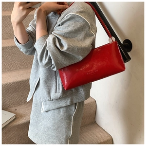 Detail of red glossy leather shoulder bag with transparent sphere ornament and brand logo