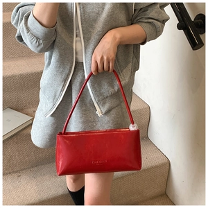 Detail of red glossy rectangular shoulder bag with transparent ball pendant on stairs