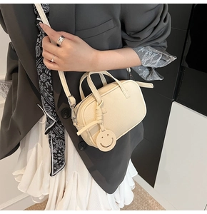Close-up of beige lychee leather crossbody bag with dual zippers and yellow smiley charm