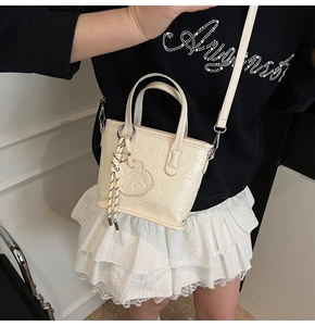 Détail du sac fourre-tout crème avec motifs de chiots gaufrés et pendentif mignon