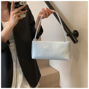 Detail of light grey glossy underarm bag with minimalist brand logo and slim shoulder strap