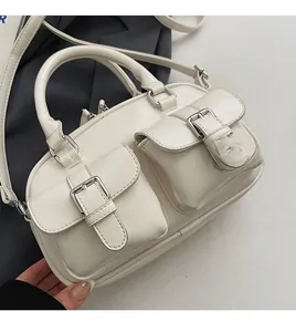 Détail du sac bowling blanc cassé avec deux poches à boucle et détails argentés