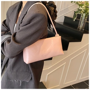 Detail of pink faux leather underarm bag with debossed logo and decorative bead accent