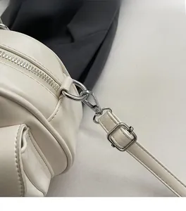 Détail des finitions argentées, du fermoir mousqueton et de la bandoulière du sac crème