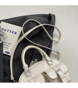 Vue détaillée du sac bowling crème montrant plusieurs poches et une texture en cuir lisse
