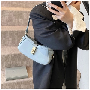 Détail du sac sous l'aisselle bleu clair brillant avec fermoir doré et bandoulière en cuir