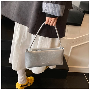 Detail of silver pleated handbag with decorative bead and brand logo on the front