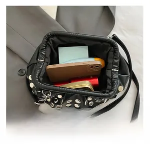Détail de l'intérieur du sac seau à rivets montrant l'espace pour téléphone et maquillage