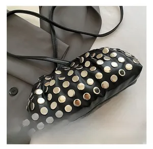 Détail des rivets argentés sur le sac à bandoulière en cuir noir avec plis chic
