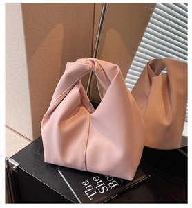 Detailed view of the twisted knot handle and soft pink PU leather on the cloud-style handbag